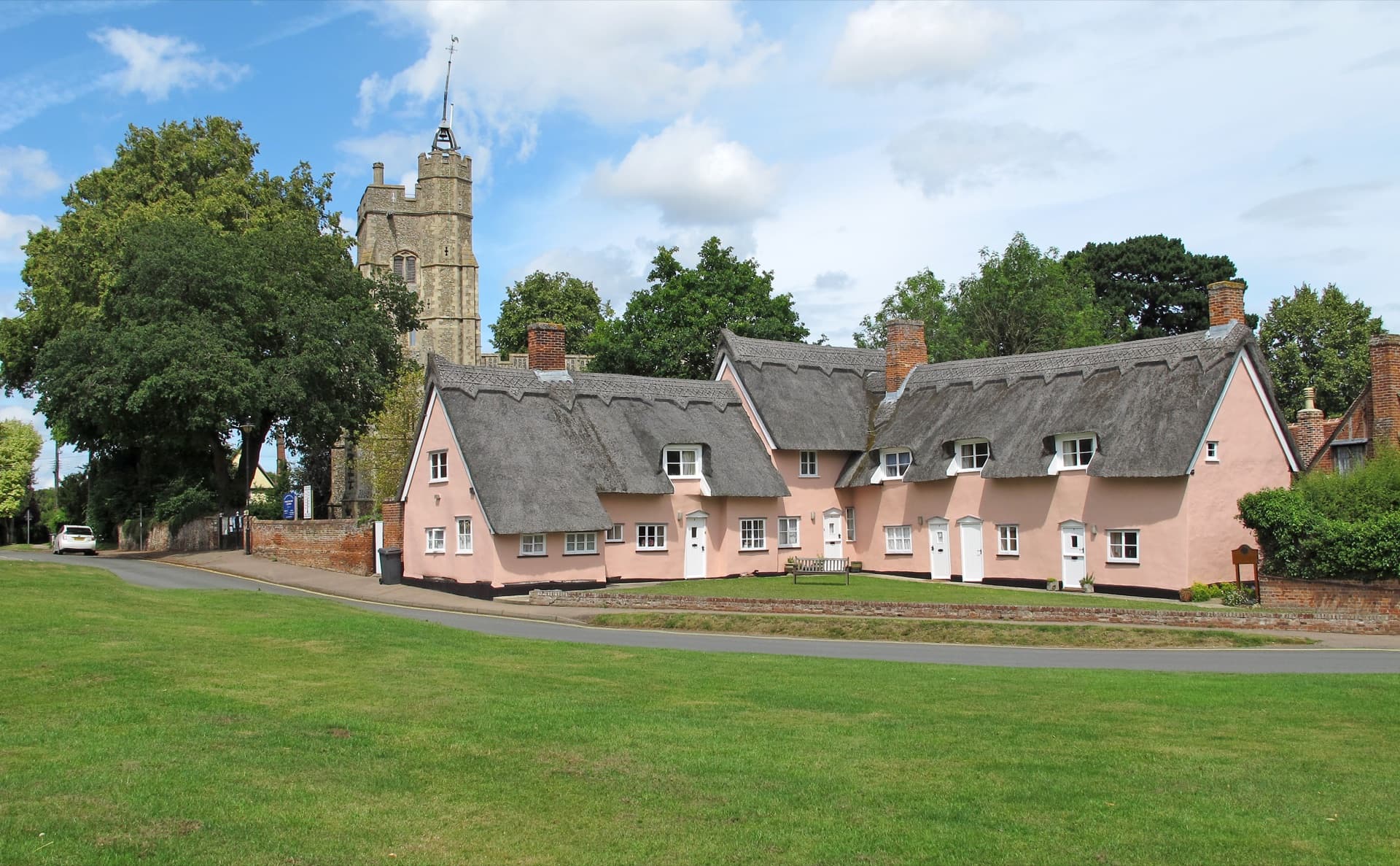 Cavendish village green, Suffolk — pink-washed thatched cottages and St Mary's church beyond, the quintessential English parish